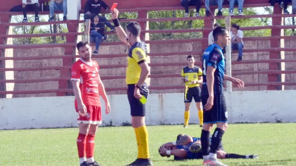 Troncoso en el piso, tomándose el rostro y su agresor, Tubesi, recibiendo la tarjeta roja.